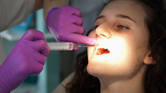 在诊所检查病人牙齿并使用针头麻醉药剂的牙科牙医视频