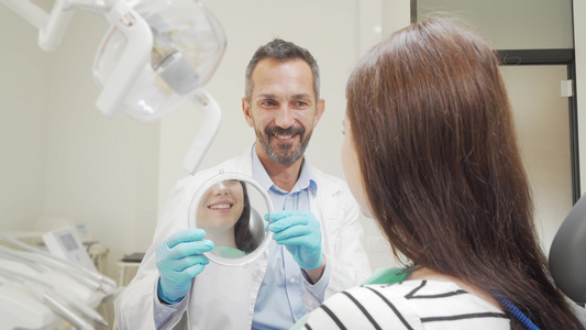 快乐的成熟牙医为他的女病人拿着镜子视频