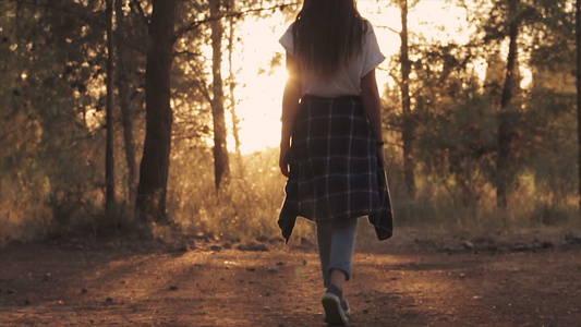 年轻女孩在森林中走向日落的后视线视频