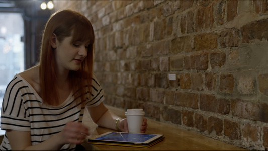 在咖啡厅喝着咖啡玩平板电脑的女人视频