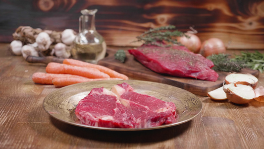 以木制背景显示两块生肉和蔬菜的慢速幻灯片移动速度视频
