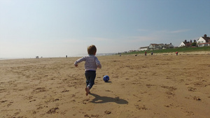 沙滩上光着脚追气球的男孩8秒视频