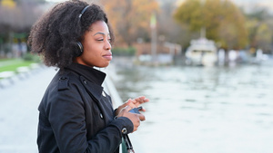 卷发女子站在河边智能手机听音乐6秒视频