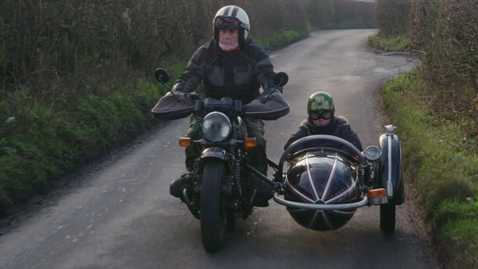 祖父和孙子骑着摩托车走在乡间的小路上视频