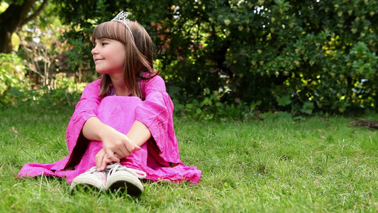 穿着粉色连衣裙带着头饰坐在草地上的女孩视频