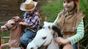 女孩和男孩打扮成美国原住民和牛仔骑在摇马上23秒视频