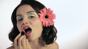 头发上带着花朵的年轻女人涂口红17秒视频