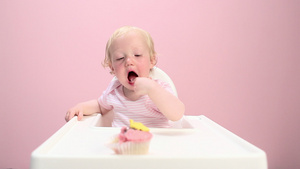 坐在高脚椅上吃纸杯蛋糕的女婴13秒视频