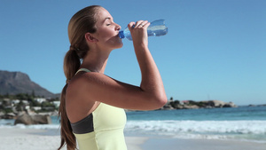 年轻女子在海滩上喝水8秒视频