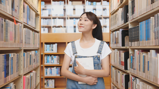 女孩在图书馆书架前选书[图书管]视频