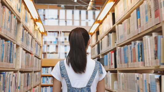 女孩在图书馆暑书架前宣选书视频