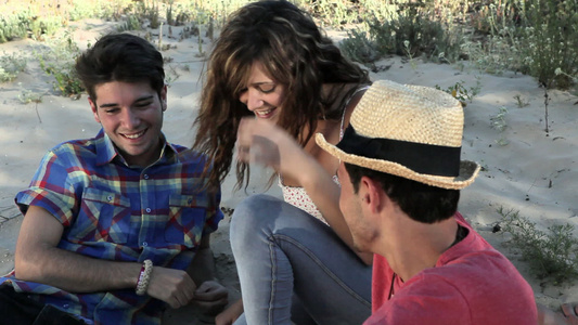 三个年轻朋友坐在海滩上视频