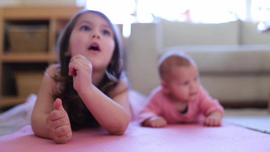 小女孩躺在她小妹妹旁边坐在粉红色地毯上视频