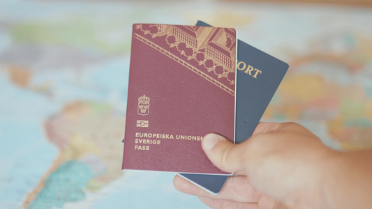 手拿着瑞典和美国护照在世界地图前视频