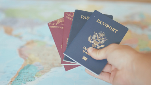 在一张多彩的世界地图前持有美国和瑞典护照的手持者视频