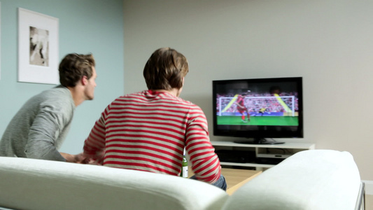 两个年轻人在电视上看足球视频