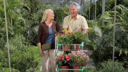 一对成熟夫妇在花园中心，手推车上满是植物视频