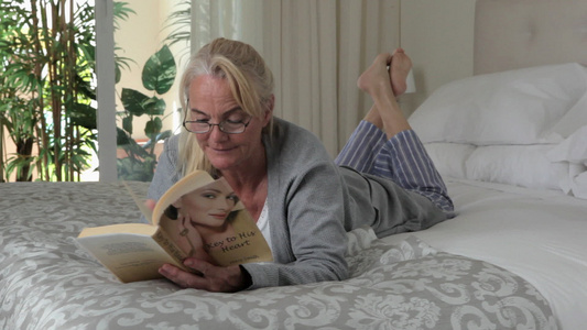 女人在床上看书，对着镜头微笑视频