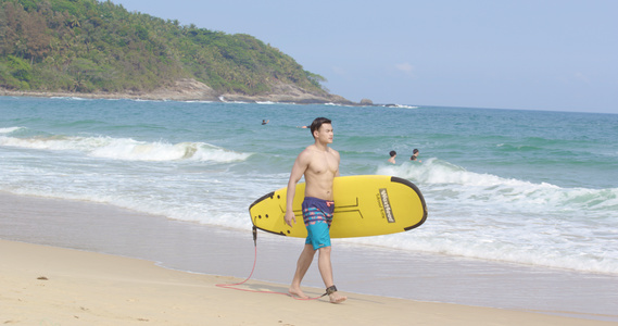 8K男青年抱着冲浪板走在沙滩上视频