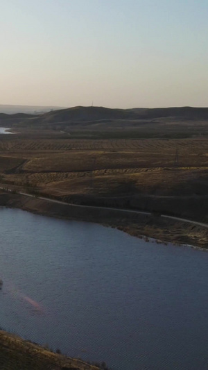 航拍夕阳下逆光的湖面和连绵起伏的山包大草原59秒视频