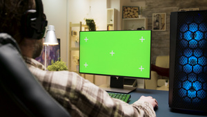 有耳机的人在电脑上玩游戏使用绿色屏幕11秒视频