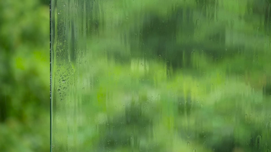 雨滴落到玻璃表面与多汁的绿绿色对着视频