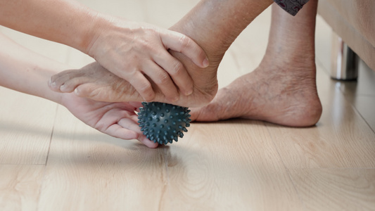 年长妇女用橡胶球锻炼手指棕榈手和脚肌肉照顾者要小心视频