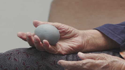 年长妇女用橡胶球锻炼手指棕榈手和脚肌肉照顾者要小心视频