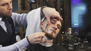 英俊的年轻人在理发店刮胡子时剃胡子14秒视频