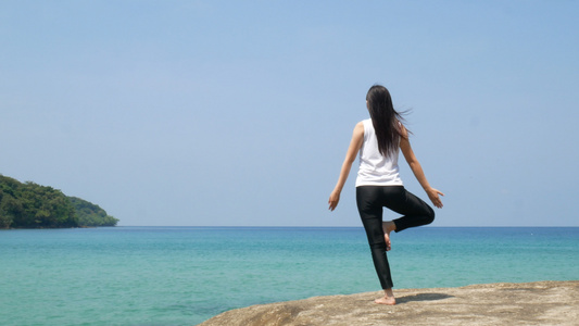 4K一个女人在暑假期间在海上的木桥上练习瑜伽时站在视频