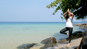 4K一个女人在暑假期间在海上的木桥上练习瑜伽时站在10秒视频