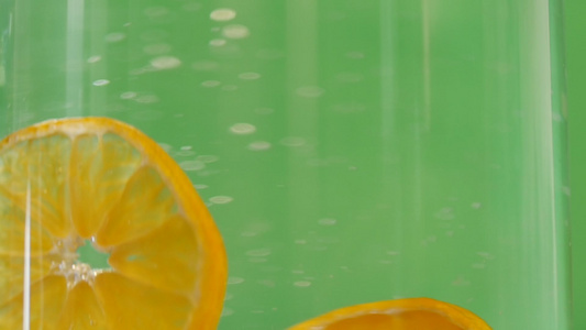克莱门汀在玻璃水中溅水绿色背景清洁新鲜有机水果以实现视频