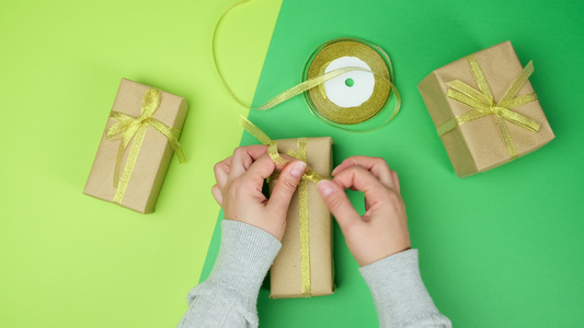 女人把礼物装在棕纸和金丝带绿色背景视频