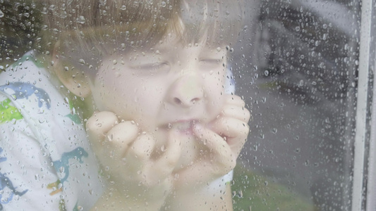 男孩在雨天从窗户向外看视频