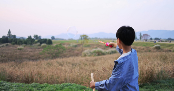 快乐的男孩在芦苇荡吹泡泡唯美慢镜头视频