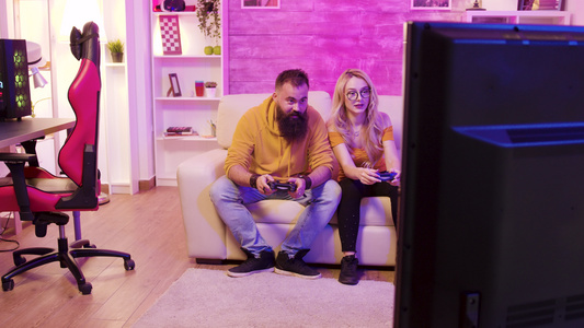 坐在沙发上玩电子游戏的一对兴奋的年轻夫妇视频