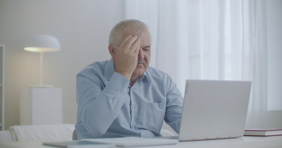男人用笔记本电脑工作会感到头痛手触额头过度劳累和疲劳视频