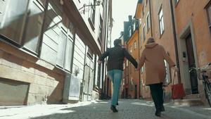 幸福的情侣在狭窄的街道上奔跑50秒视频