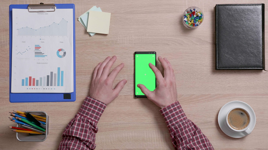 雄性手指的顶部视图放大和显示智能手机的绿色屏幕视频