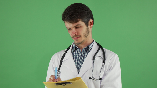 年轻男医生在他的绿色铬制染色体剪贴板上写作视频