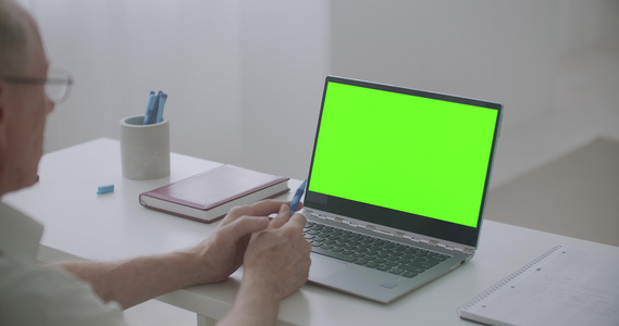 退休男子使用笔记本电脑与视频聊天Pc上绿色屏幕进行视频