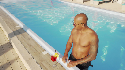 英俊的非洲男人喜欢在游泳池喝鸡尾酒视频