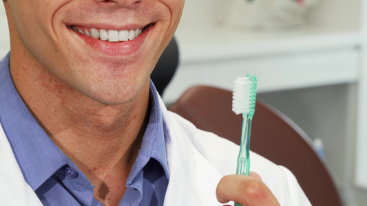 男性牙医笑着带着牙刷的完美牙齿视频