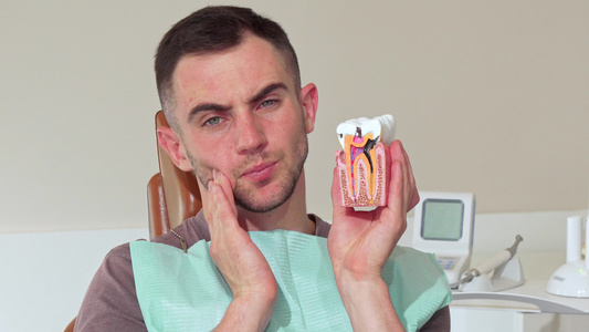 年轻男子牙痛坐在诊所的牙科椅上;男视频