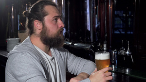 长胡子长头发长发的男人看着忧郁独自在酒吧喝啤酒17秒视频