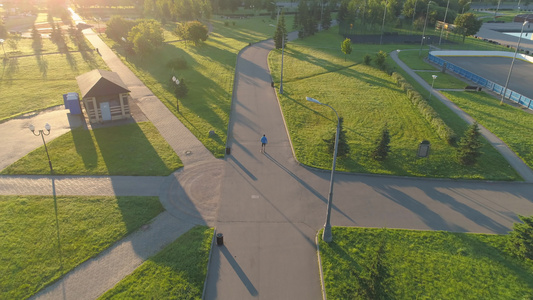 男人在阳光明媚的清晨在绿色城市公园滚动着视频