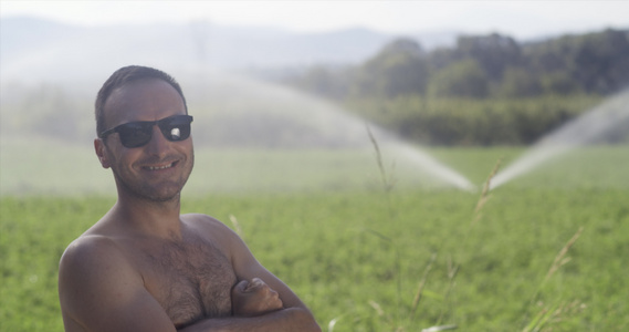 农用农业工人没有衬衫在有灌溉系统的绿田上没有衬衣背景视频