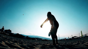 一个少年男孩在海滩打网球的慢动作21秒视频