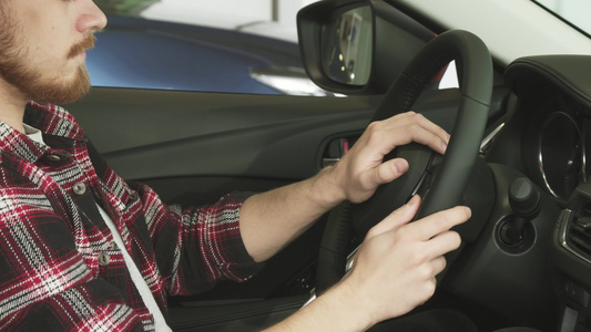 一名长胡子的男子坐在一辆手持方向盘的汽车上视频
