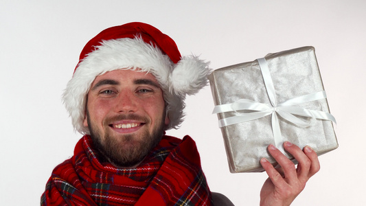 穿着圣诞节帽子的英俊长胡子男子笑着微笑举着礼物视频